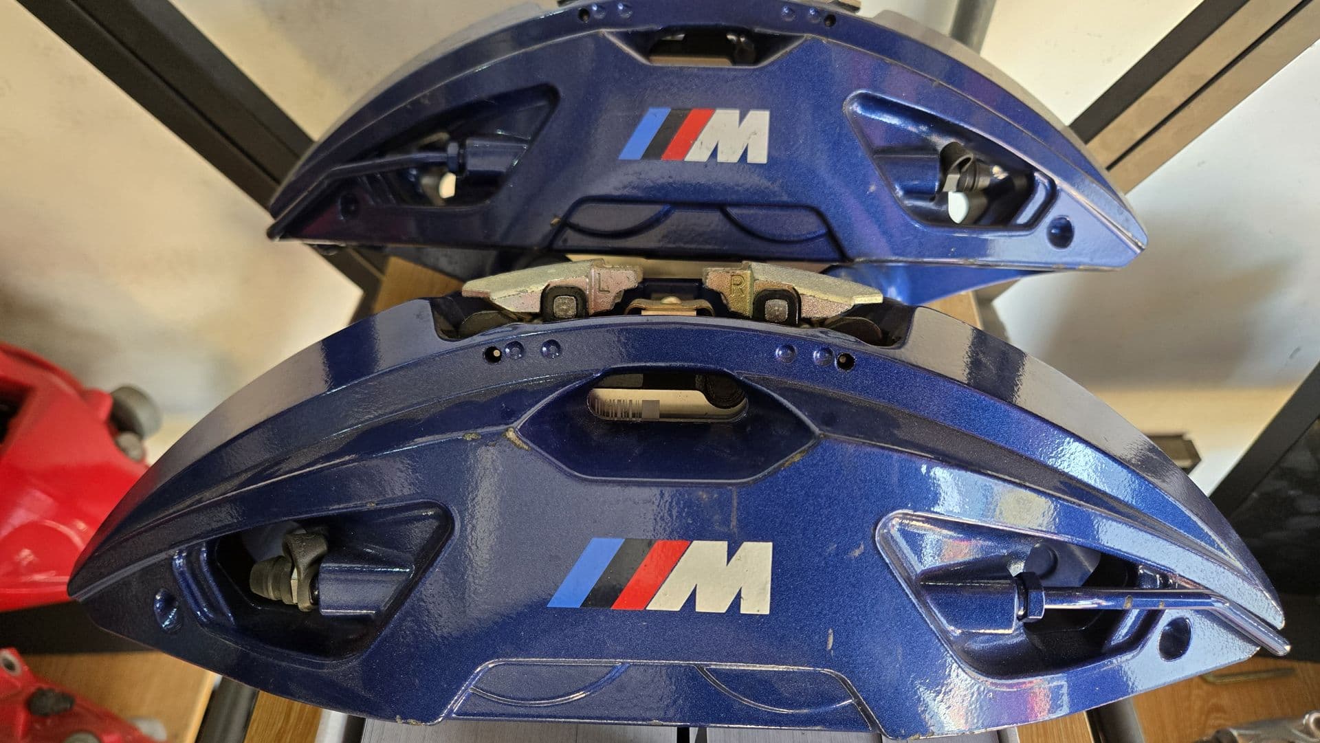 Blue BMW M brake calipers on a shelf